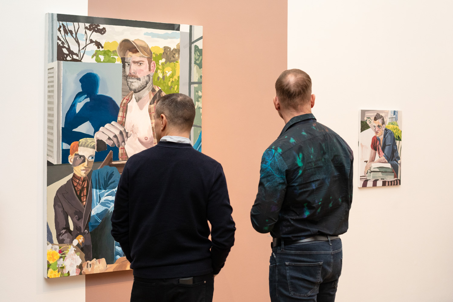 David Lock: In-between Us at Firstsite. Photograph by Jayne Lloyd. Photograph of David Lock's exhibition at Firstsite gallery, showing one large painting to the left and a smaller piece to the right. The wall is white with a strip of peach painted behind the larger piece. The backs of two people with short hair and dark clothing in front can be seen as they look at the exhibition.